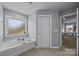 The large soaking tub has natural light from the frosted window and a door to the main bathroom at 9871 Travertine Trl, Davidson, NC 28036