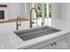 A close-up of a kitchen island featuring a undermount sink with brass faucets and a waterfall countertop at 114 Wilharr Ct # 38, Mooresville, NC 28115