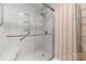 Modern glass-enclosed shower with a built-in seat, handrails, and tiled walls at 12117 Idlewild Rd, Matthews, NC 28105