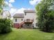 View of the home's back exterior featuring a deck, stairs, manicured lawn, and mature trees at 12317 Panthersville Dr, Charlotte, NC 28269