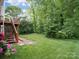 Backyard featuring lush green grass, a wooden staircase, and mature trees offering shade and privacy at 12317 Panthersville Dr, Charlotte, NC 28269
