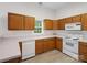 Traditional kitchen featuring wood cabinets, white appliances, and a window over the sink at 12317 Panthersville Dr, Charlotte, NC 28269