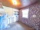 View of utility room with water heater, shelving, and brick accent wall and window at 1468 Hilltop St, Albemarle, NC 28001