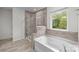 Relaxing bathroom featuring a glass-enclosed shower, soaking tub, and large window with a view at 1601 Calder Dr, Indian Trail, NC 28079