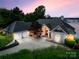 Inviting home exterior with a three-car garage, manicured landscaping, and stunning twilight lighting at 16108 Woolwine Rd, Charlotte, NC 28278