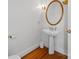 Stylish powder room features a pedestal sink, gold mirror and hardwood floors at 16108 Woolwine Rd, Charlotte, NC 28278