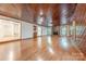 Spacious living room featuring hardwood floors, a brick fireplace, wood-paneled walls, and abundant natural light at 2310 Vestry Pl, Charlotte, NC 28270