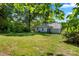 A spacious backyard features lush green grass, mature trees, and a quaint single-story home with light blue siding at 2635 Clover Hill Ln, Charlotte, NC 28215