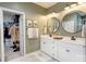 Bathroom featuring dual vanities, round mirrors, and a door leading to a walk-in closet at 3424 Saint Clair Nw Ct, Concord, NC 28027