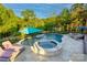 Backyard kidney bean-shaped pool and hot tub, surrounding deck, blue umbrellas, and wooded surround at 3424 Saint Clair Nw Ct, Concord, NC 28027