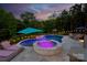Inviting pool with spa, travertine tile, manicured landscaping, and relaxing lounge chairs at dusk at 3424 Saint Clair Nw Ct, Concord, NC 28027