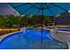 Inviting pool with spa featuring travertine tile and a relaxing waterfall feature at dusk at 3424 Saint Clair Nw Ct, Concord, NC 28027