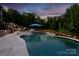 Inviting pool with spa, travertine tile, manicured landscaping, and relaxing lounge chairs at dusk at 3424 Saint Clair Nw Ct, Concord, NC 28027