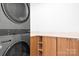 Modern laundry room with stacked washer and dryer and built-in wood cabinets for easy access at 4316 Old Saybrook Ct, Charlotte, NC 28211