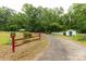 View of a property with a shed, surrounded by mature trees and a red rail fence at 439 Kershaw Country Club Rd, Kershaw, SC 29067