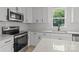 Bright kitchen featuring white cabinets, stainless steel appliances, and speckled granite countertops at 518 Herms Ave, Mount Holly, NC 28120