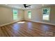 Spacious bedroom with wood-look flooring, ceiling fan, and three bright windows at 603 Turnberry Ct, Albemarle, NC 28001
