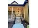 A close up of the covered porch showing classic lighting and brick steps leading to a glass front door at 603 Turnberry Ct, Albemarle, NC 28001