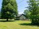 Exterior view showcasing the home's setting, with a deck nestled in a lush yard with mature trees at 7728 Babe Stillwell Farm Rd, Huntersville, NC 28078