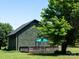 Exterior view of a home with green siding, black trim, and a back deck surrounded by trees and grass at 7728 Babe Stillwell Farm Rd, Huntersville, NC 28078