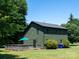 Exterior view of a home with green siding, black trim, and a back deck, surrounded by trees and a lush lawn at 7728 Babe Stillwell Farm Rd, Huntersville, NC 28078