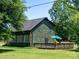 A view of the home's green exterior with a deck and umbrella on a lush green lawn at 7728 Babe Stillwell Farm Rd, Huntersville, NC 28078