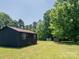 Outbuilding with a single door sits on a lush green lot with mature trees at 7728 Babe Stillwell Farm Rd, Huntersville, NC 28078
