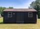 A dark-colored shed with a brown roof with a door and window accents at 7728 Babe Stillwell Farm Rd, Huntersville, NC 28078