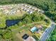 A scenic aerial view of a neighborhood featuring a pond, pool, clubhouse, and tree-lined streets at 8268 Breton Way, Harrisburg, NC 28075