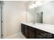 Well-lit bathroom featuring a dark vanity cabinet, white countertops, and a large mirror reflecting the doorway at 8268 Breton Way, Harrisburg, NC 28075