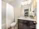 Bright bathroom with a shower-tub combo, toilet, dark vanity featuring a sink and countertop at 8268 Breton Way, Harrisburg, NC 28075