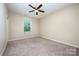 Neutral bedroom with a large window, a ceiling fan, and carpet flooring provides ample natural light at 8268 Breton Way, Harrisburg, NC 28075