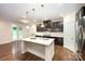 Kitchen featuring a large island with quartz countertops, dark cabinets, and stainless steel appliances at 8268 Breton Way, Harrisburg, NC 28075