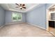 This main bedroom features a tray ceiling, ceiling fan, neutral carpet, and a view into the main bath at 8268 Breton Way, Harrisburg, NC 28075