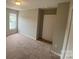 A neutral-toned bedroom features a window letting in natural light and plush carpet at 118 Steam Engine Dr # 201, Mooresville, NC 28115