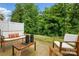 Charming patio with cozy seating, wood furniture, string lights, and a view of lush green foliage at 12021 Basking Dr, Charlotte, NC 28214