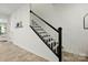 Staircase with dark-stained steps and white risers, white walls, and light-colored wood floors at 12021 Basking Dr, Charlotte, NC 28214