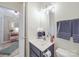 A bathroom with an open doorway with a white countertop, blue cabinet, and decorative mirror and lighting at 135 Henry Putnam Dr, Cherryville, NC 28021