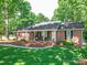 Charming one-story brick home featuring a cozy covered front porch with seating and manicured landscaping at 135 Henry Putnam Dr, Cherryville, NC 28021