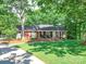 Charming brick home with covered porch, black shutters, mature trees, and lush green lawn at 135 Henry Putnam Dr, Cherryville, NC 28021