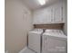 Functional laundry room equipped with a white washer and dryer and overhead cabinets at 135 Henry Putnam Dr, Cherryville, NC 28021