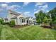 Expansive backyard featuring lush lawn, patio seating, and meticulously landscaped garden beds with mature trees at 13602 Huntson Park Ln, Huntersville, NC 28078