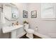 Tastefully designed powder room featuring a pedestal sink, modern fixtures, stylish mirror, and neutral color palette at 13602 Huntson Park Ln, Huntersville, NC 28078