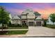 Charming two-story home at dusk features stone accents, a two-car garage, and manicured landscaping at 13602 Huntson Park Ln, Huntersville, NC 28078