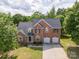 Aerial view of brick home with a three car garage and a well maintained front lawn at 1465 Porters Ct, Concord, NC 28025