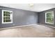 Spacious bedroom with neutral carpet, gray walls, bright light fixture and two windows at 1465 Porters Ct, Concord, NC 28025