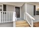 Close-up view of a front porch featuring fresh wood stairs, white banister, and sleek black door at 1637 Sumner Dr, Rock Hill, SC 29732