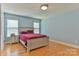 Bright bedroom features light blue walls, wood laminate flooring, and a comfortable bed with a red velvet cover at 206 Pine Meadow St, Hickory, NC 28601
