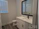 Modern bathroom with a white vanity, marble countertop, black fixtures, and wood-look flooring at 2068 Fordhill St, Rock Hill, SC 29732