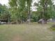 Expansive backyard with mature trees and storage sheds along the fence line at 2213 Milton Rd, Charlotte, NC 28215